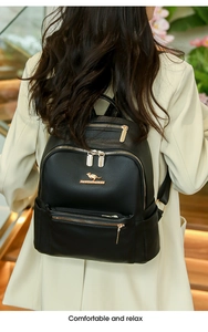 Detail of black PU leather backpack with gold zippers and metal logo on a model in-store