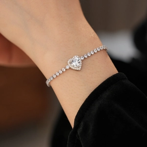 Macro shot of a sparkling heart-shaped zircon tennis bracelet on a model's wrist