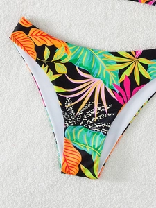 Close-up of tropical palm leaf and leopard print patchwork on bikini swim bottoms