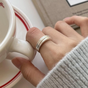 Close-up of minimalist layered S925 sterling silver ring on hand with coffee cup