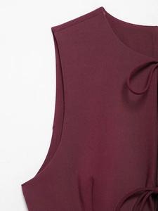 Detailed macro view of burgundy sleeveless dress featuring a bow tie neckline and twill texture