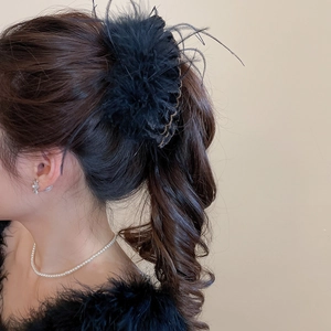 Detail of fluffy black feather hair clip on model with elegant pearl necklace styling