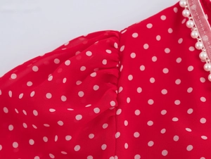 Dettaglio macro del tessuto in chiffon a pois rossi con elegante bordo in perle