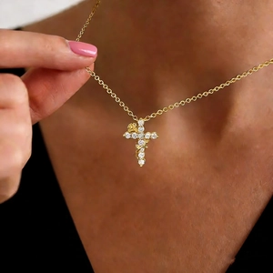 Elegant gold cross pendant necklace featuring floral vine details and sparkling crystals