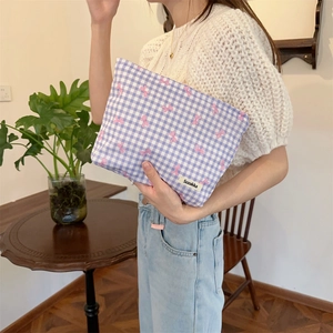 Detail of purple gingham pouch with pink bows held by a model in a cozy setting