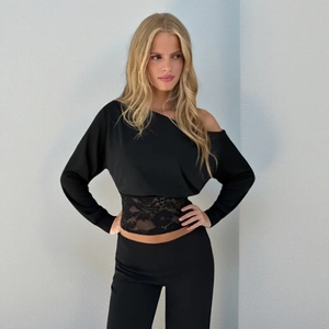 Detail of black off-shoulder top featuring intricate floral lace patchwork at the waist