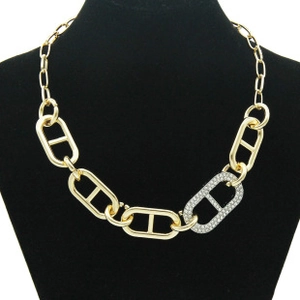 Detail of a gold pig-nose link necklace with sparkling rhinestones on black velvet stand