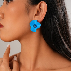 Macro shot of blue flower stud earring with square crystal centerpiece on a model