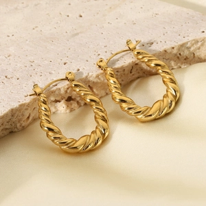Detailed view of gold plated stainless steel twisted earrings on a natural stone base