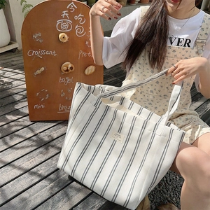Detail of canvas tote bag showing black vertical stripes and cream fabric texture