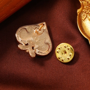 Creative spade design gold-tone metal collar pin brooch on a dark textured fabric background