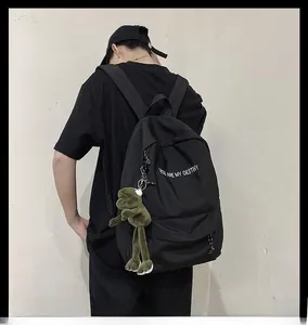 Détail du sac à dos en nylon noir avec imprimé et breloque peluche grenouille verte
