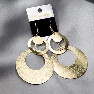 Detail of layered gold hollowed geometric earrings on a black fashion jewelry card