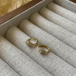 Elegant gold petal hoop earrings with pavé crystals on a luxury jewelry box
