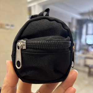 Close-up of mini backpack coin purse in black canvas with metal zipper and keyring