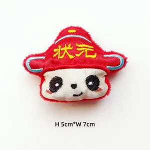 Dettaglio ravvicinato di una spilla a forma di panda con cappello rosso tradizionale
