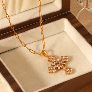 Gros plan d'un collier croix doré orné de zircons dans un écrin à bijoux en bois chic