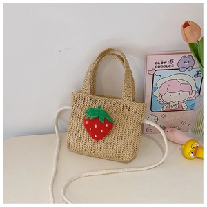Detail of straw woven mini bag featuring red strawberry accent and dual carry straps
