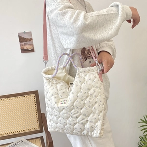 Gros plan d'un sac à main matelassé à fleurs avec motif violet et bandoulière rose