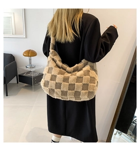 Detailed view of the large plush checkerboard tote bag worn over the shoulder.