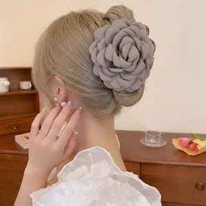 Elegant grey fabric camellia flower hair claw clip for bun hairstyles on model