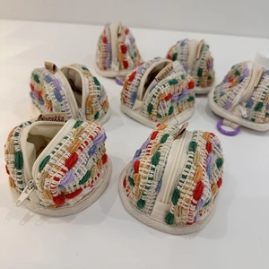 Close-up of colorful hand-woven mini earphone pouches with white zipper and fabric label