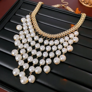 Dettaglio di collana di perle bianche multistrato con catene dorate su vassoio nero
