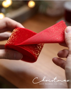 Close-up of red velvet Christmas ribbon with gold glitter and white stitched edges