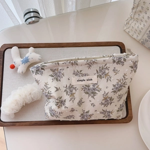 Detail of floral makeup bag featuring simple wish tag and smooth metal zipper