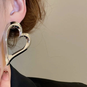 Macro shot of large polished silver heart earrings worn by a model in detail
