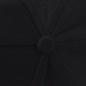 Macro shot of the black cotton twill texture and top button detail of the baseball cap