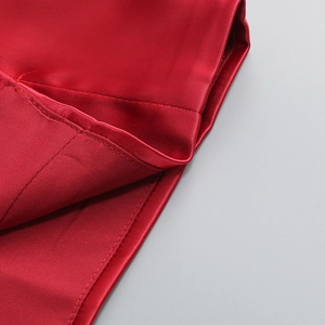 Gros plan détaillé du tissu en satin rouge avec coutures précises et finition de l'ourlet