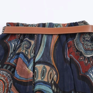 Detail eines Midi-Kleides mit Boho-Print, goldenen Lurexfäden und einem braunen Gürtel