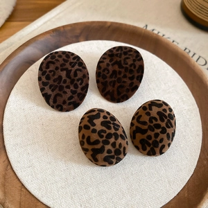 Oval leopard print earrings with flocked velvet texture on a decorative display
