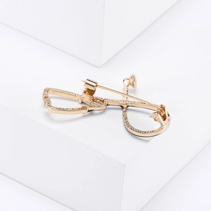 Detailed view of a gold stethoscope brooch with sparkling crystals on white background