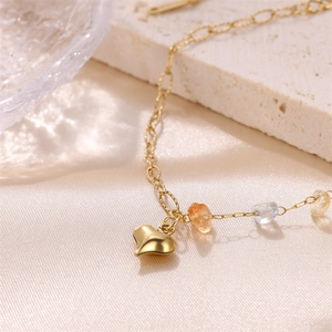 Golden heart charm bracelet with natural crushed gemstones on a soft silk and stone backdrop