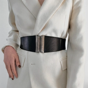 Detail of a vintage black wide waist belt with double silver metal buckles on a white suit