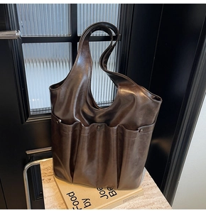 Detail view of large dark brown leather tote bag with functional pockets and glossy finish
