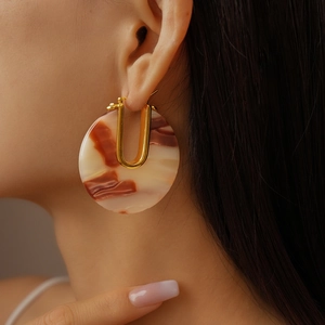 Macro view of a marbled acetate hoop earring with a 18k gold-plated U-shaped accent