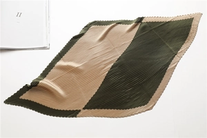 Detailed close-up of dark green and khaki pleated scarf with geometric patchwork