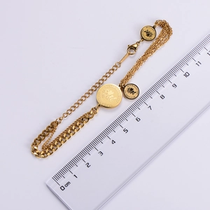 Close-up of golden multilayer chain bracelet with Elizabeth II coin pendant and measurement
