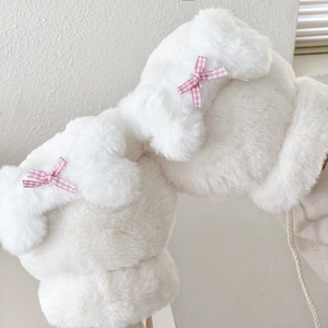 Dettaglio di guanti di peluche bianchi con fiocchi a scacchi rosa e morbida ecopelliccia
