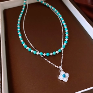 Macro detail of turquoise beads and clover pendant on vintage layered silver necklace