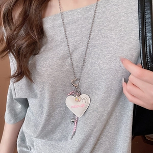 Detail of silver beaded necklace featuring a cream heart pendant and pink bow charm