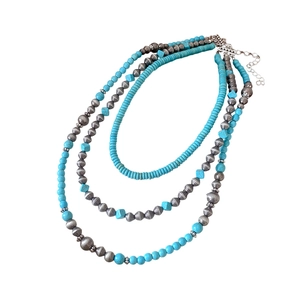 Three-layer bohemian necklace featuring silver beads and turquoise stones on a white background