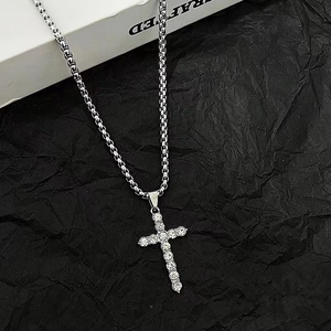 Hiphop silver cross necklace with pavé diamonds on box chain over black textured background