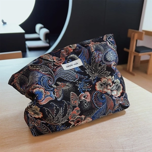 Detail of floral brocade makeup bag with intricate jacquard patterns and logo label