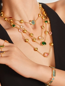 Detail of layered gold stainless steel necklace with colorful faceted glass stones