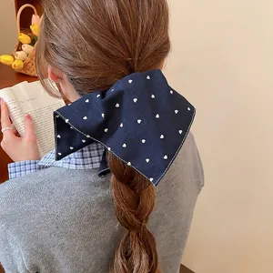 Pince à cheveux élégante en tissu bleu marine à motifs cœurs blancs sur une femme