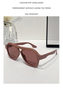 Detail view of retro pilot sunglasses with thick khaki frames on a minimalist white surface